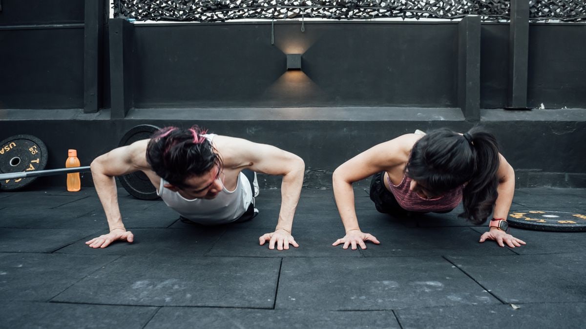Two adults doing push-ups in an indoor gym setting in Mexico City, promoting a fit and healthy lifestyle.